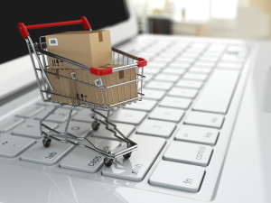E-commerce. Shopping cart with cardboard boxes on laptop.